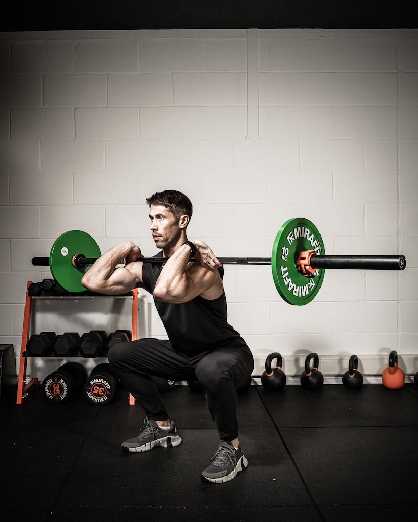 PT demonstrating how to do a barbell front squat as part of a metabolic resistance training workout