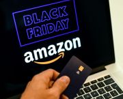 Close up of a man holding a credit card by a laptop screen advertising Black Friday