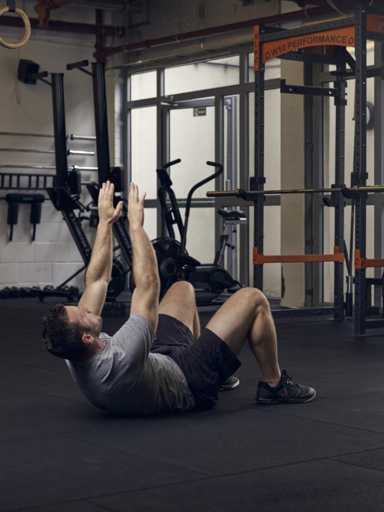 man demonstrates crunch reach, one of the best bodyweight exercises for core strength