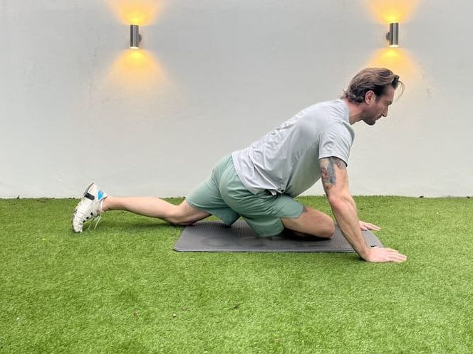 man demonstrates how to do dynamic pigeon, one of the best stretches for beginners