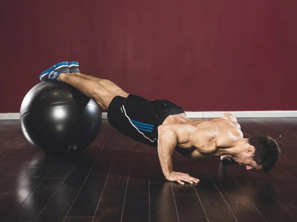 Man performing a gym ball decline push-up exercise