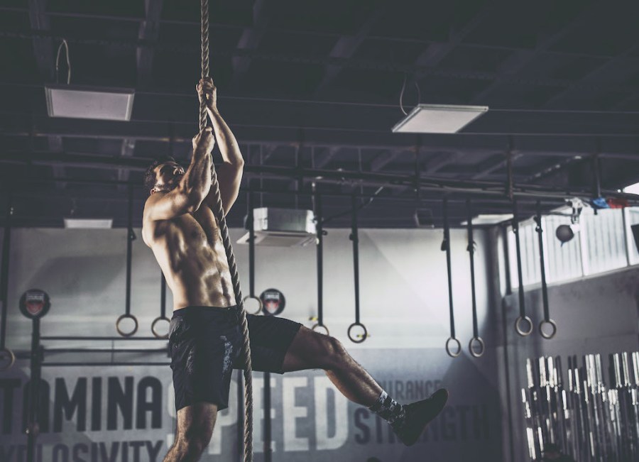 Topless man performing rope climb