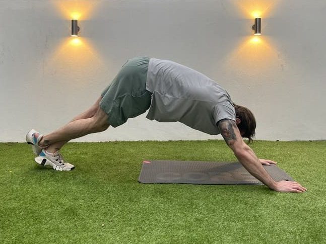 man demonstrates how to do a hip lift ankle stretch.