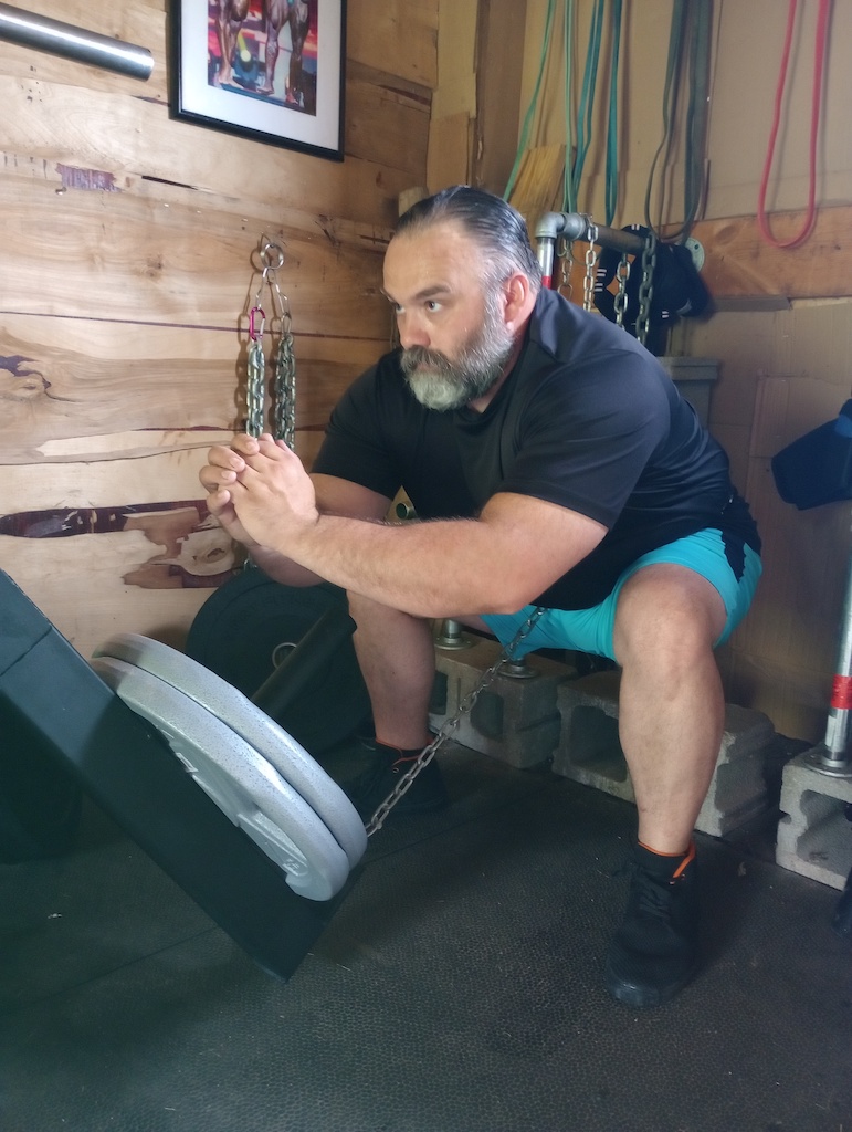 man performing plate-loaded squat with the Signature Fitness Lever Arm Rack Attachment