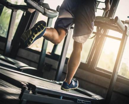 Lower half of man running on treadmill