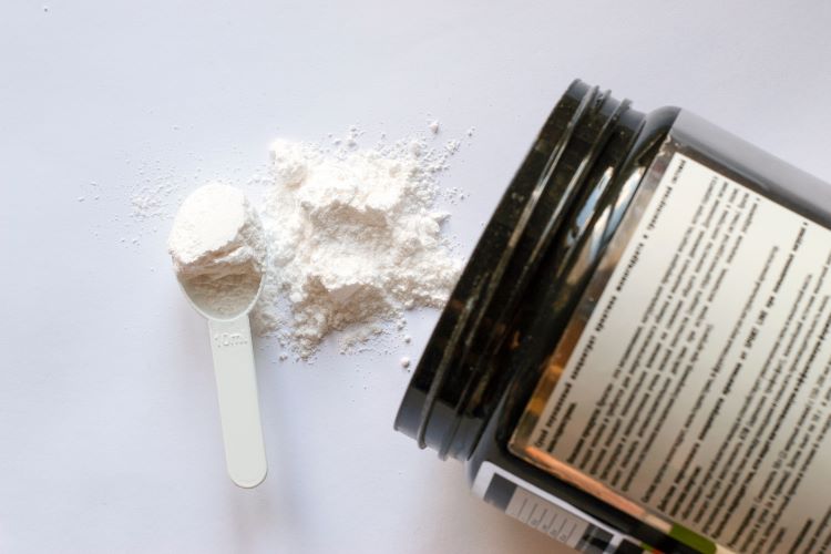 A tub and scoop of white pre-workout powder