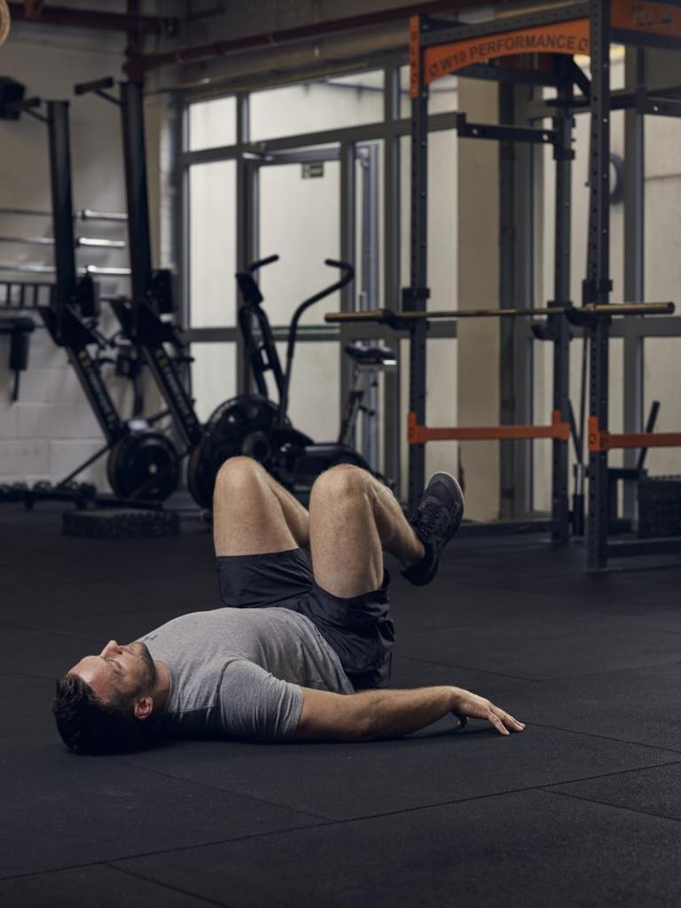 man demonstrates reverse crunch, one of the best bodyweight exercises for core strength