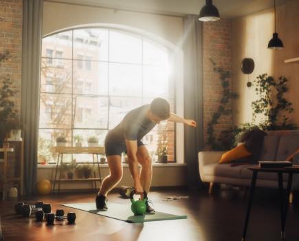 athletic man working out at home using a kettlebell