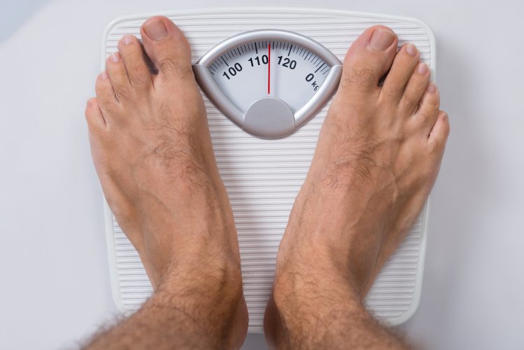 A pair or men's feet standing on a set of weighing scales