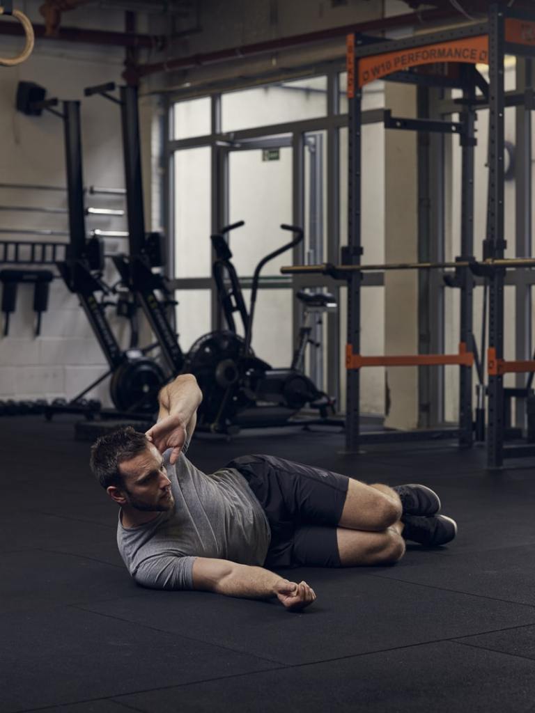 man demonstrates side crunch, one of the best bodyweight exercises for core strength