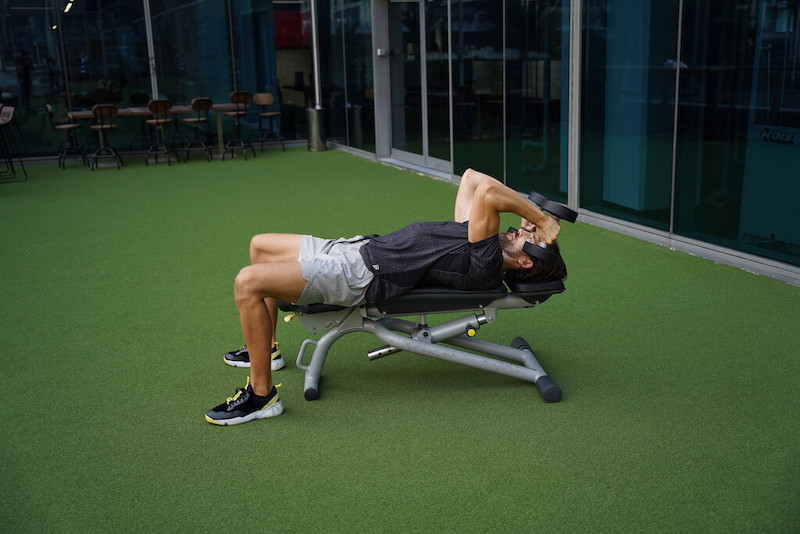man demonstrating dumbbell skull crusher triceps exercise